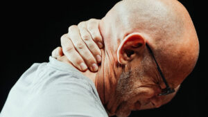 side view of a man with neck pain holding his neck